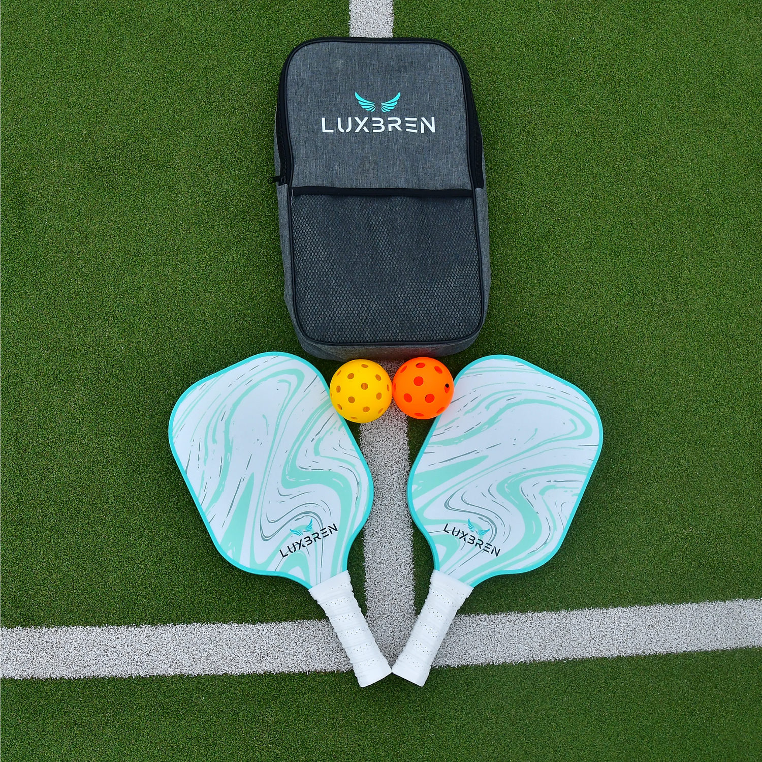Luxbren pickleball equipment set featuring 2 pickleball paddles, 4 pickleballs, and a grey pickleball bag on a outdoor green tennis court