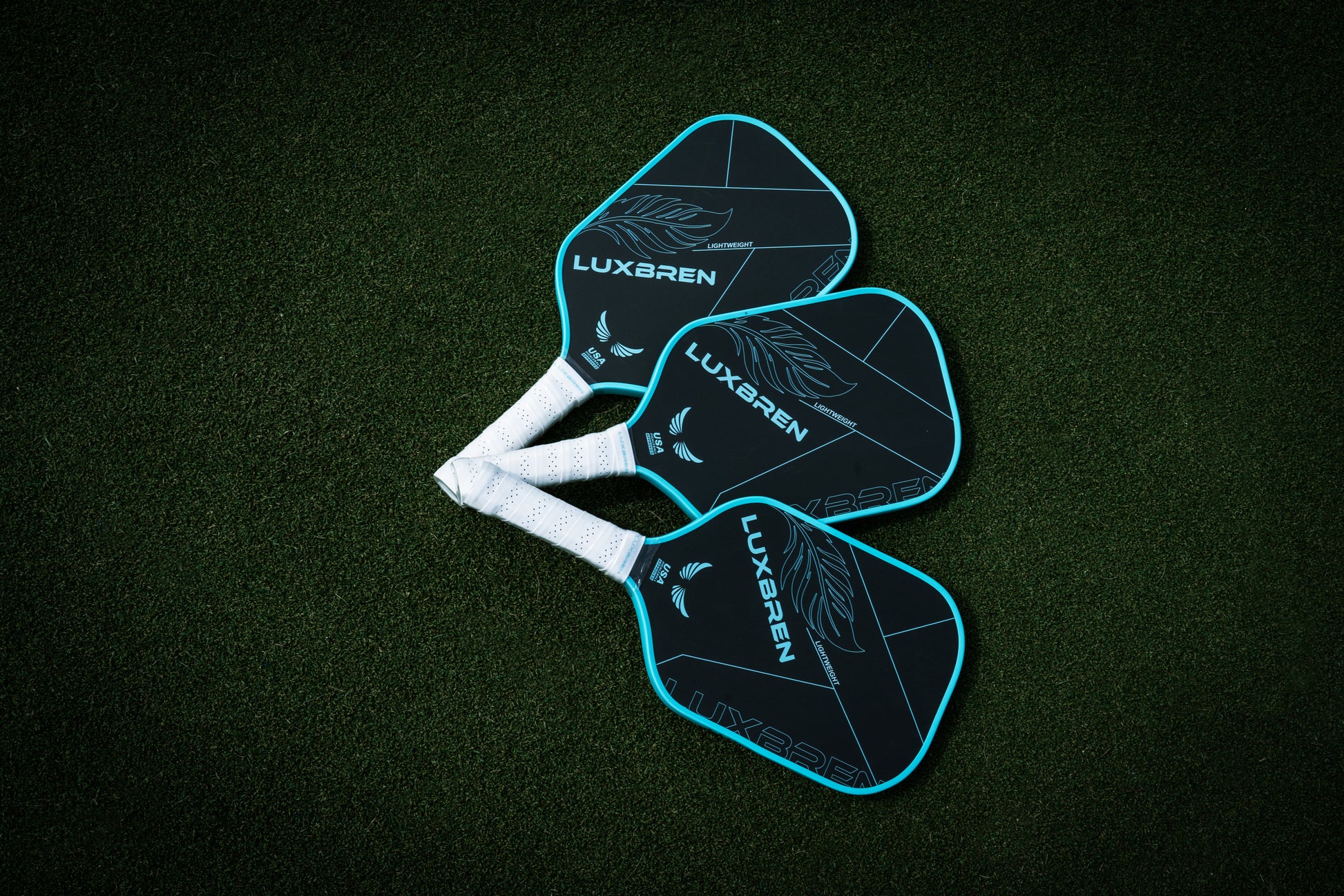Three Luxgren pickleball paddles on a dark green background